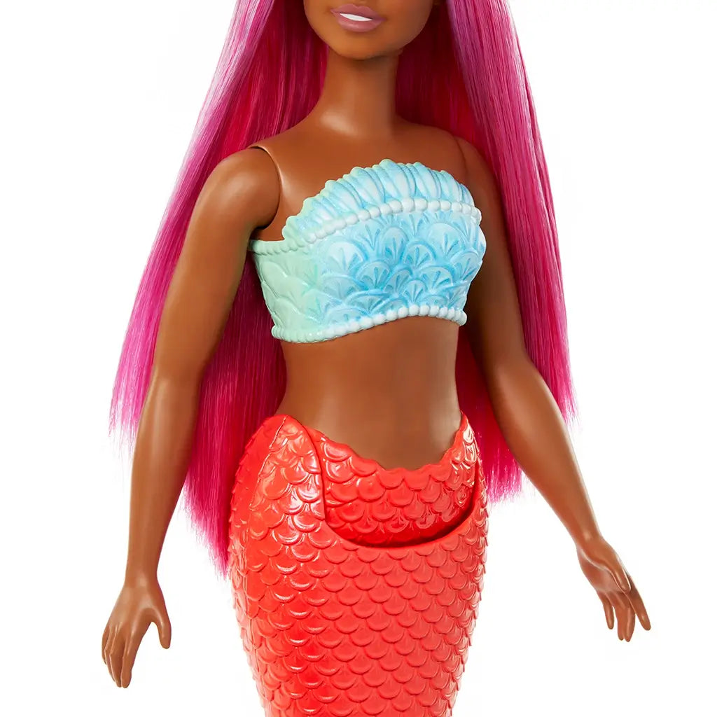 Barbie mermaid torso close-up showing turquoise seashell-style bandeau with textured trim, paired with bright red scale-pattern mermaid tail, accented by long magenta hair.