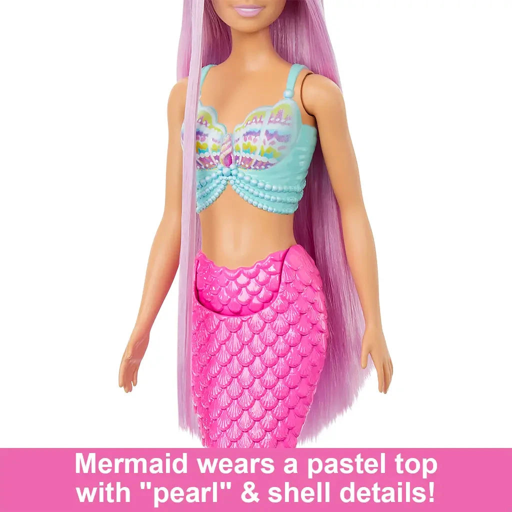 Close-up of Barbie mermaid doll’s outfit showing pastel-colored top with pearl and shell details and a sculpted pink mermaid tail with scale texture.