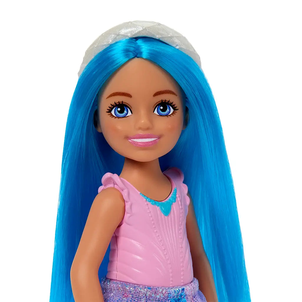 Barbie Chelsea doll with long straight blue hair, sparkling blue eyes, and a pink top, wearing a silver tiara-style headband and soft makeup for a princess-inspired look.