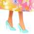 Close-up of Barbie doll’s feet wearing glossy mint high-heeled shoes with scalloped edges and butterfly details, shown under a colorful butterfly-print skirt.