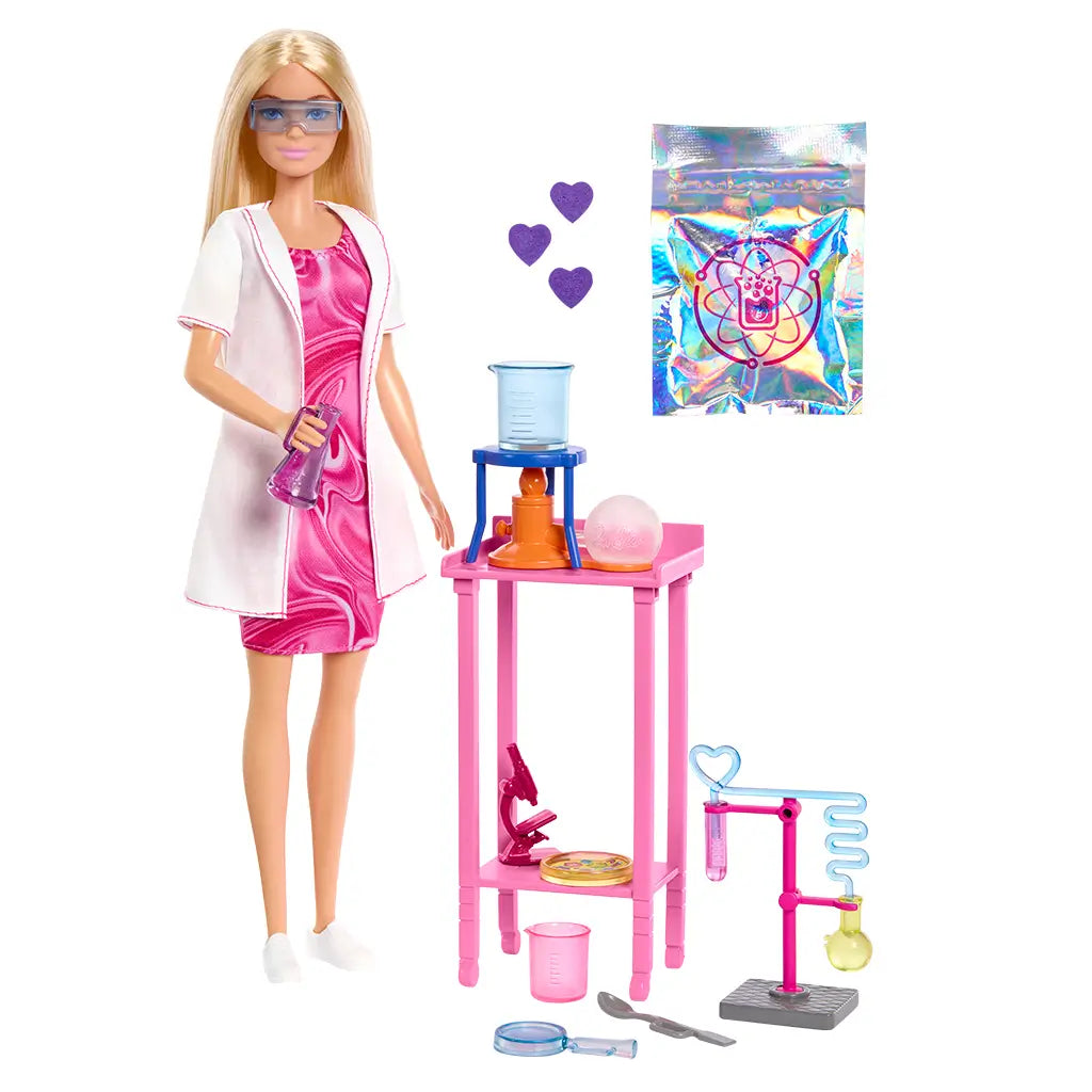 Barbie Scientist Doll in pink dress and white lab coat standing next to pink lab table with toy microscope, flasks, beaker, and experiment accessories for imaginative STEM roleplay.