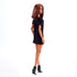 Barbie Signature Basics 2025 Series 1 Model 01 doll rear angled view showing straight brown hair, black shift dress, and sleek black ankle boots against a plain white background.