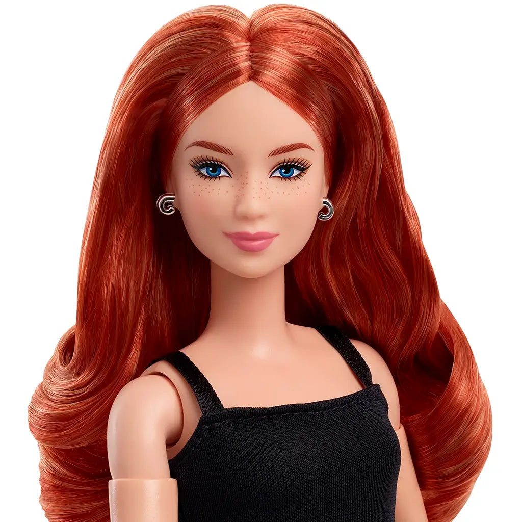 Barbie Signature Basics 2025 Model 4 fashion doll with long wavy red hair, blue eyes, freckles, silver hoop earrings, and black spaghetti strap dress against white background.