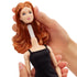 Close-up of Barbie Signature Basics 2025 Model 4 fashion doll head being removed, revealing white neck connector mechanism, doll wearing black dress and styled red hair.