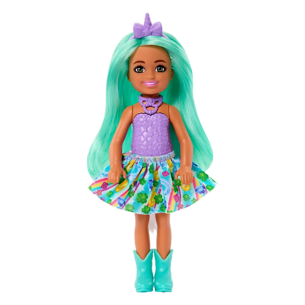 Barbie Chelsea doll with long mint green hair wears a lavender textured top, multicolor printed skirt, turquoise boots, and a unicorn horn headband, posed on white background.