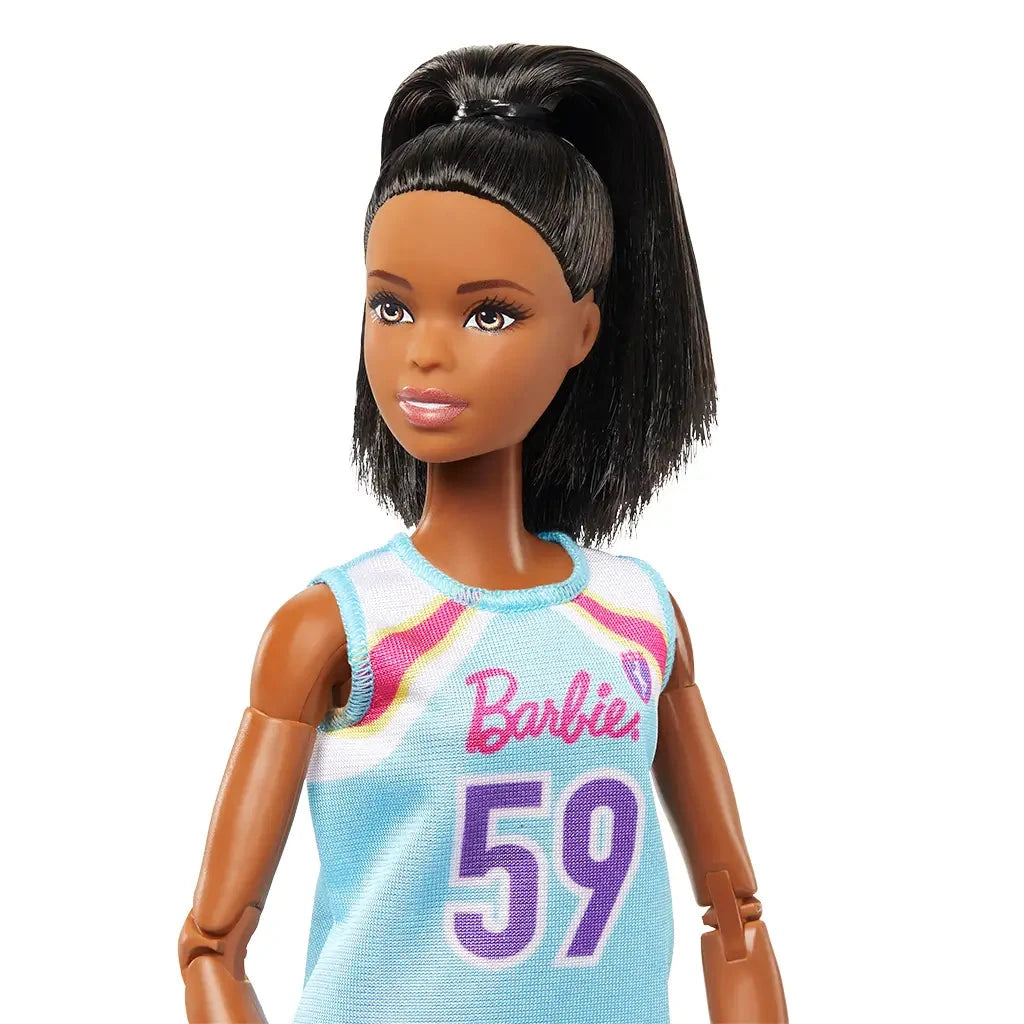 Close-up of Barbie basketball doll’s face, featuring detailed facial features, straight black hair in a high ponytail, and a sporty blue jersey with pink and purple accents.