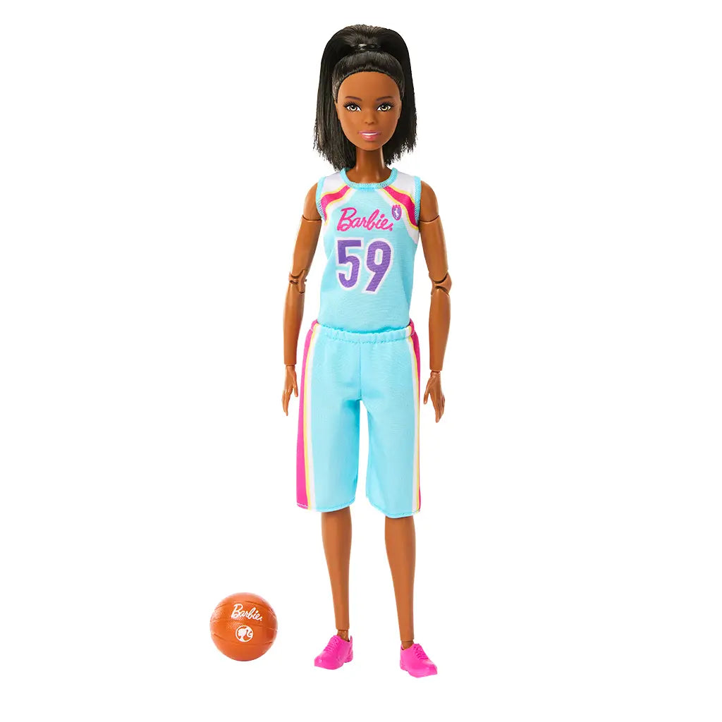 Barbie basketball player doll standing next to an orange basketball, dressed ready to play in a removable team uniform with a colorful jersey marked '59', shorts, and pink sneakers.