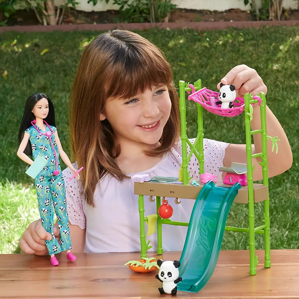 Barbie panda care playset with a girl playing, featuring green bamboo-themed structure, slide, hammock, and panda figures for imaginative rescue and vet storytelling fun.