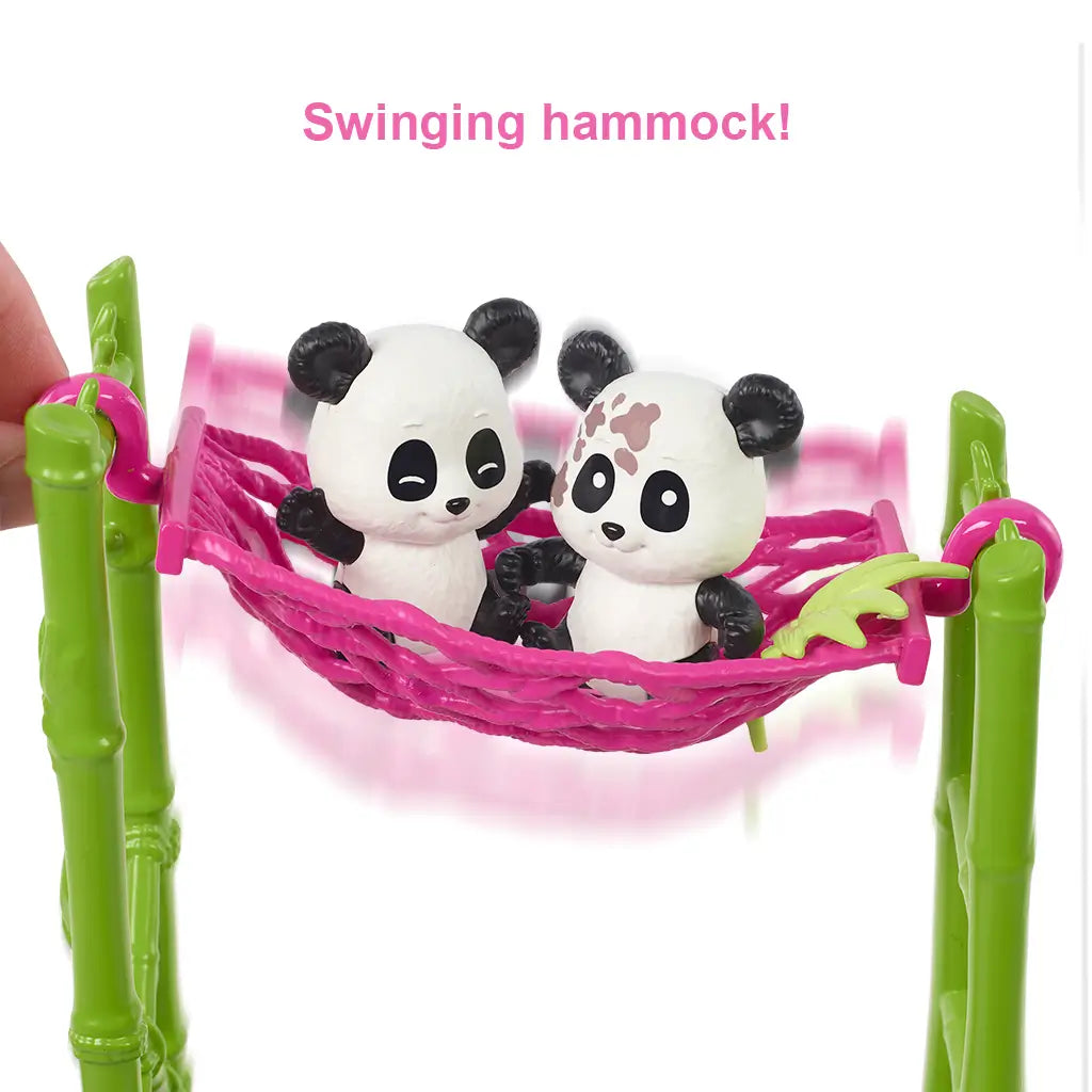 Close-up of two panda toy figures sitting in a bright pink hammock attached to green bamboo poles, showcasing the swinging play feature of the Barbie panda care playset.