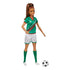 Barbie soccer player doll in green jersey with red accents, white shorts, and green socks, standing beside a black-and-white soccer ball, with long brown hair in ponytail.