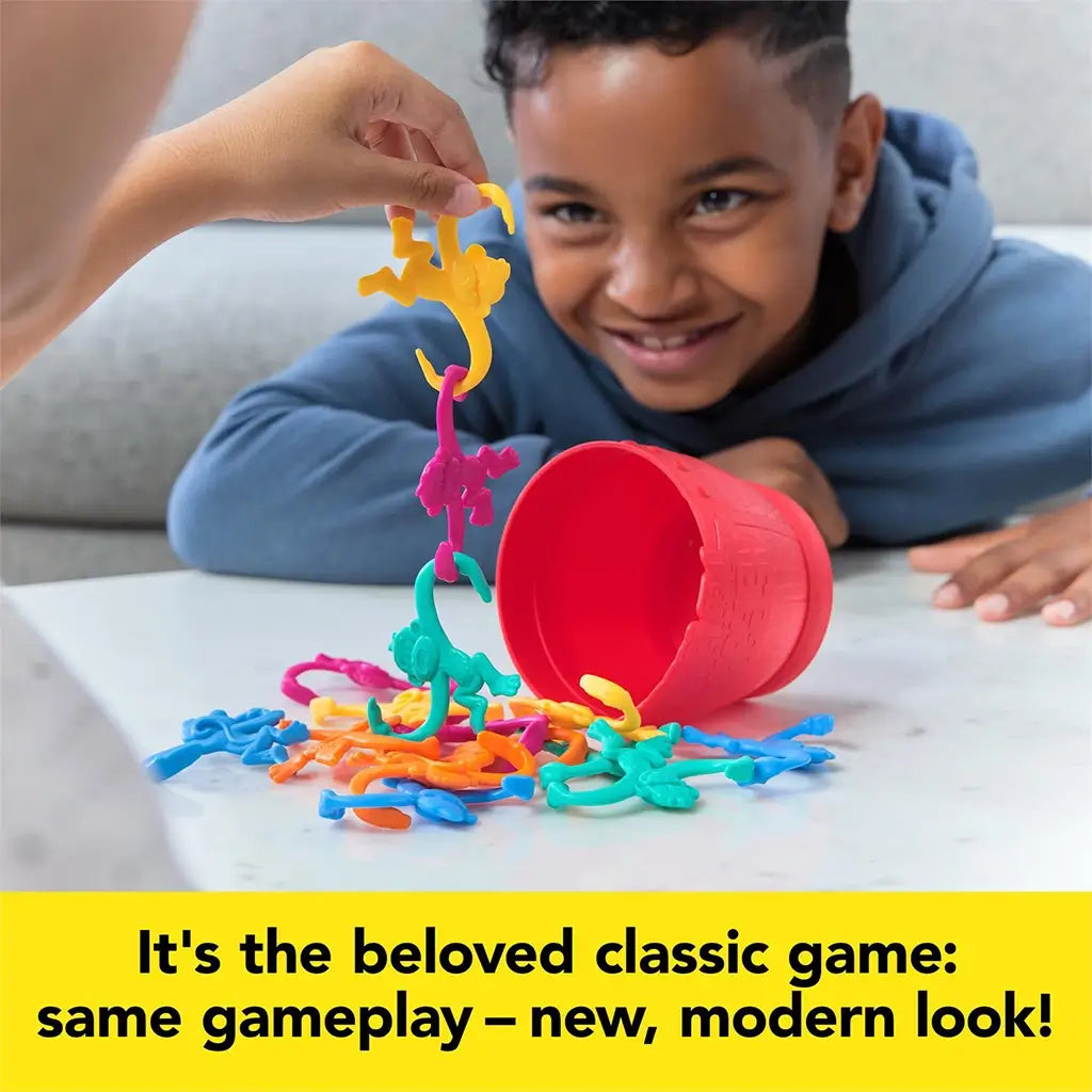 A smiling child watches as colorful monkeys are linked together from the Barrel of Monkeys set, showing the game’s fun and competitive play.