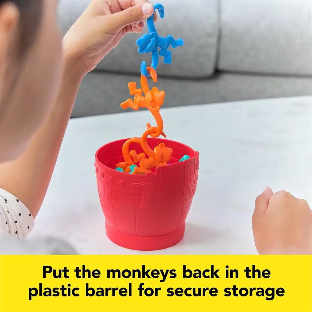 Child placing brightly colored monkeys back into the red Barrel of Monkeys container, showing easy storage and cleanup after play.