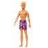 Side-angled view of Beach Ken doll with blond hair, colorful geometric-patterned swim trunks, and a friendly smile.