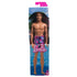 Beach Ken doll with blond hair wearing colorful purple, pink, and blue swim trunks, displayed in packaging with poolside background.