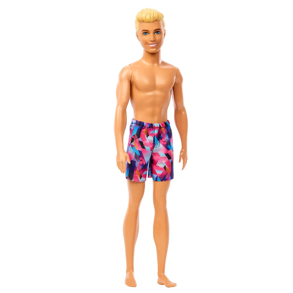 Angled front view of Beach Ken doll with blond hair and colorful purple geometric swim trunks, smiling and barefoot.