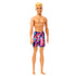 Angled front view of Beach Ken doll with blond hair and colorful purple geometric swim trunks, smiling and barefoot.