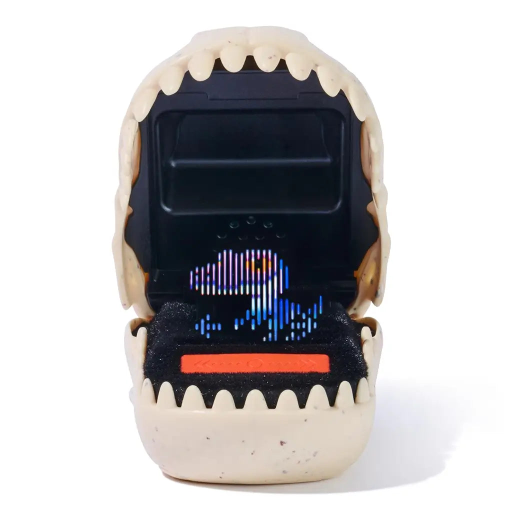 Jurassic World Bitzee digital pet device in beige molded plastic shaped like an open dinosaur jaw, featuring a black screen with bright multicolor pixel dinosaur character animation inside, photographed on white.