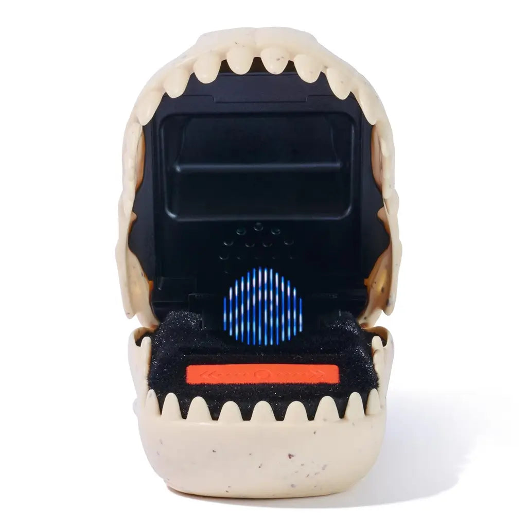 Jurassic World Bitzee digital pet toy featuring a cream-colored plastic dinosaur mouth form with rounded teeth, soft speckled texture, and a glowing pixel dinosaur animation displayed on the internal screen.