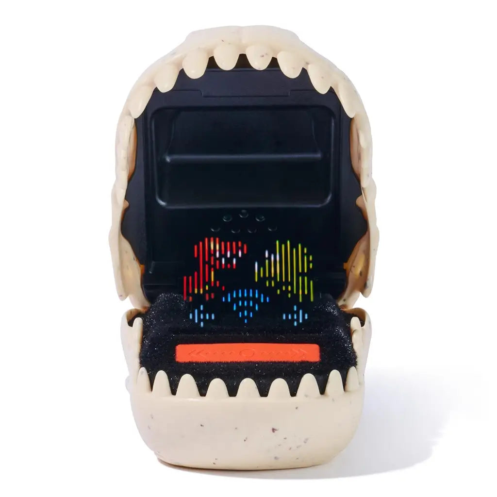 Jurassic World Bitzee digital pet toy showing a beige speckled plastic dinosaur mouth with textured teeth and a black interior, displaying colorful pixel dinosaur animations on an LED screen against a white background.