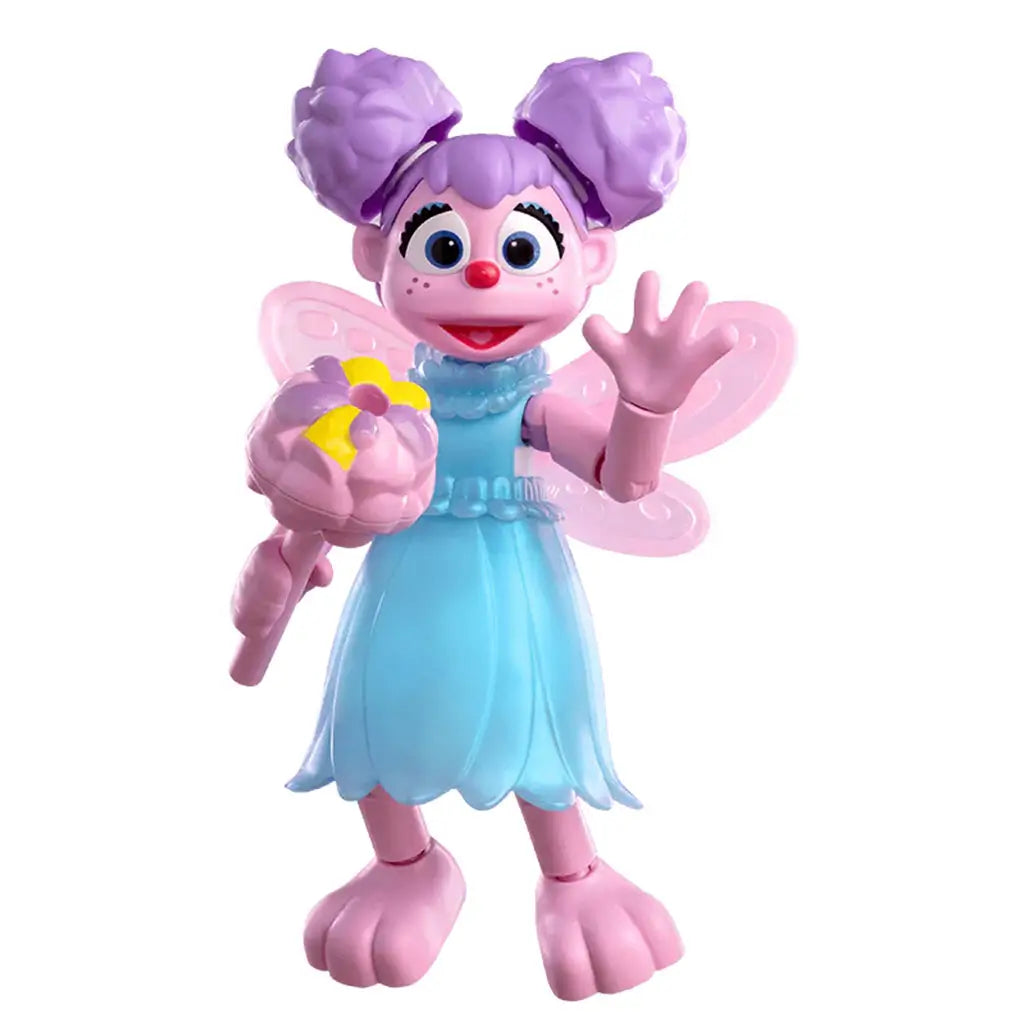 Blokees Abby Cadabby plastic figure featuring bright pink skin, lavender hair in pigtails, blue petal-style dress, pink fairy wings, and holding a pink and yellow wand while smiling cheerfully.
