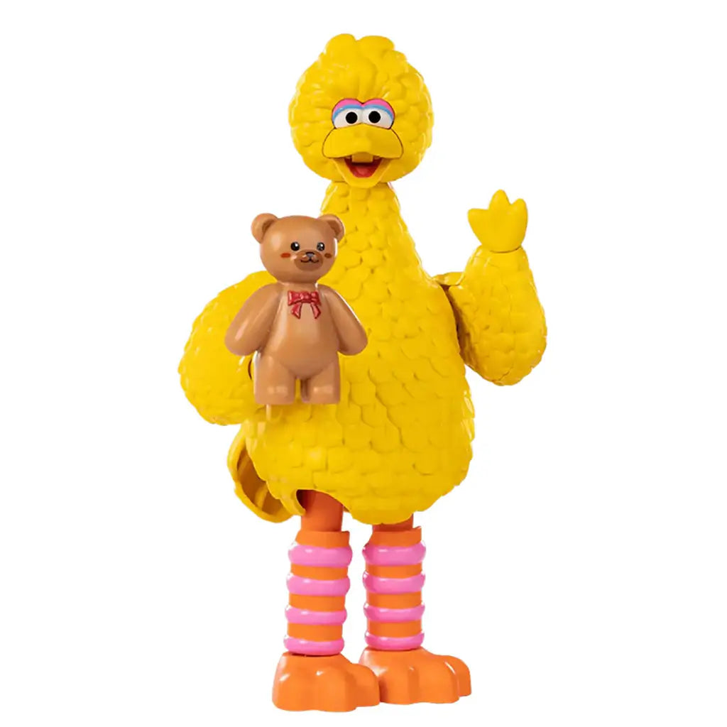 Yellow plastic Big Bird toy figure from Sesame Street holding a brown teddy bear with a red bow, featuring textured feather details, striped orange and pink legs, and a friendly waving pose.