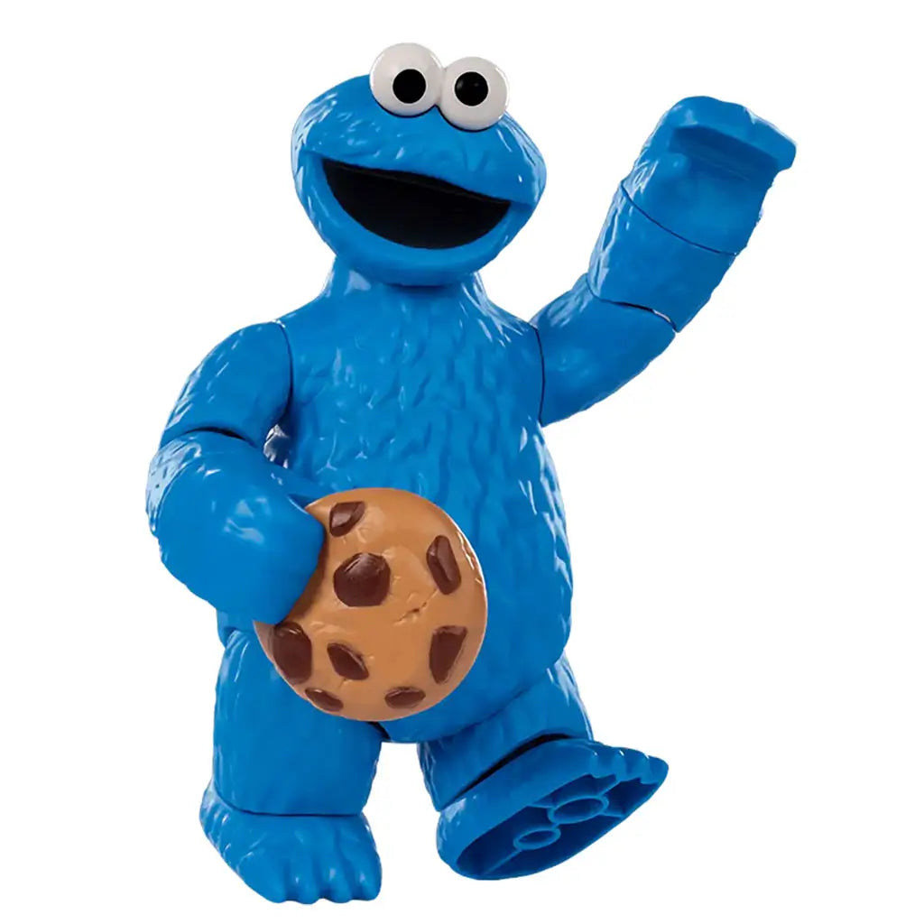 Blue plastic Cookie Monster toy figure from Sesame Street waving cheerfully while holding a brown cookie with chocolate chips, showing textured fur details and a playful expression.