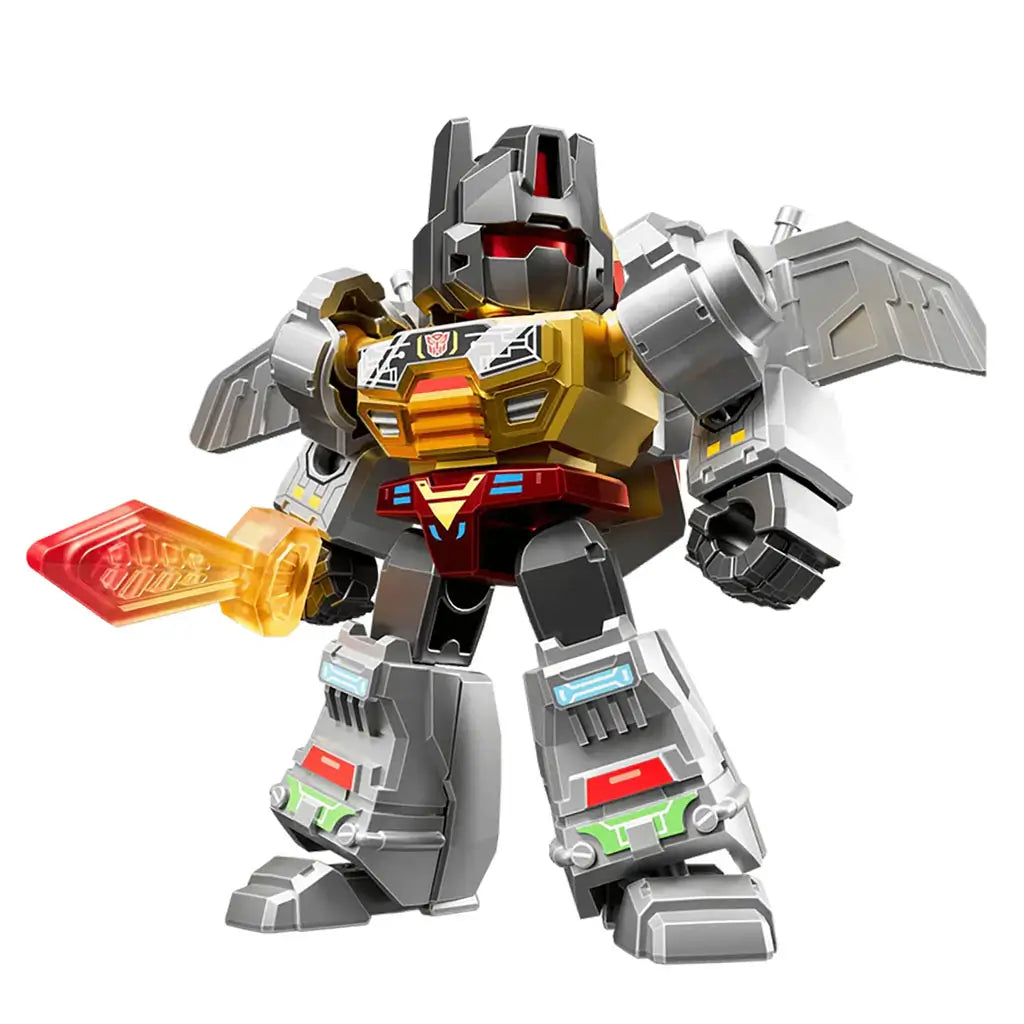 Transformers toy figure with metallic silver and gold plastic body, blocky sculpted armor shapes, heroic combat pose, and clear red blade held in a raised hand against a plain white backdrop.