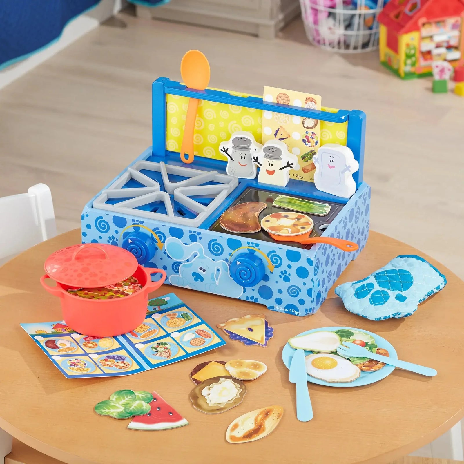 Blue’s Clues-themed toy cooking set on a table with red pot, pretend food, utensils, sink, stove, recipe cards, and colorful play pieces.