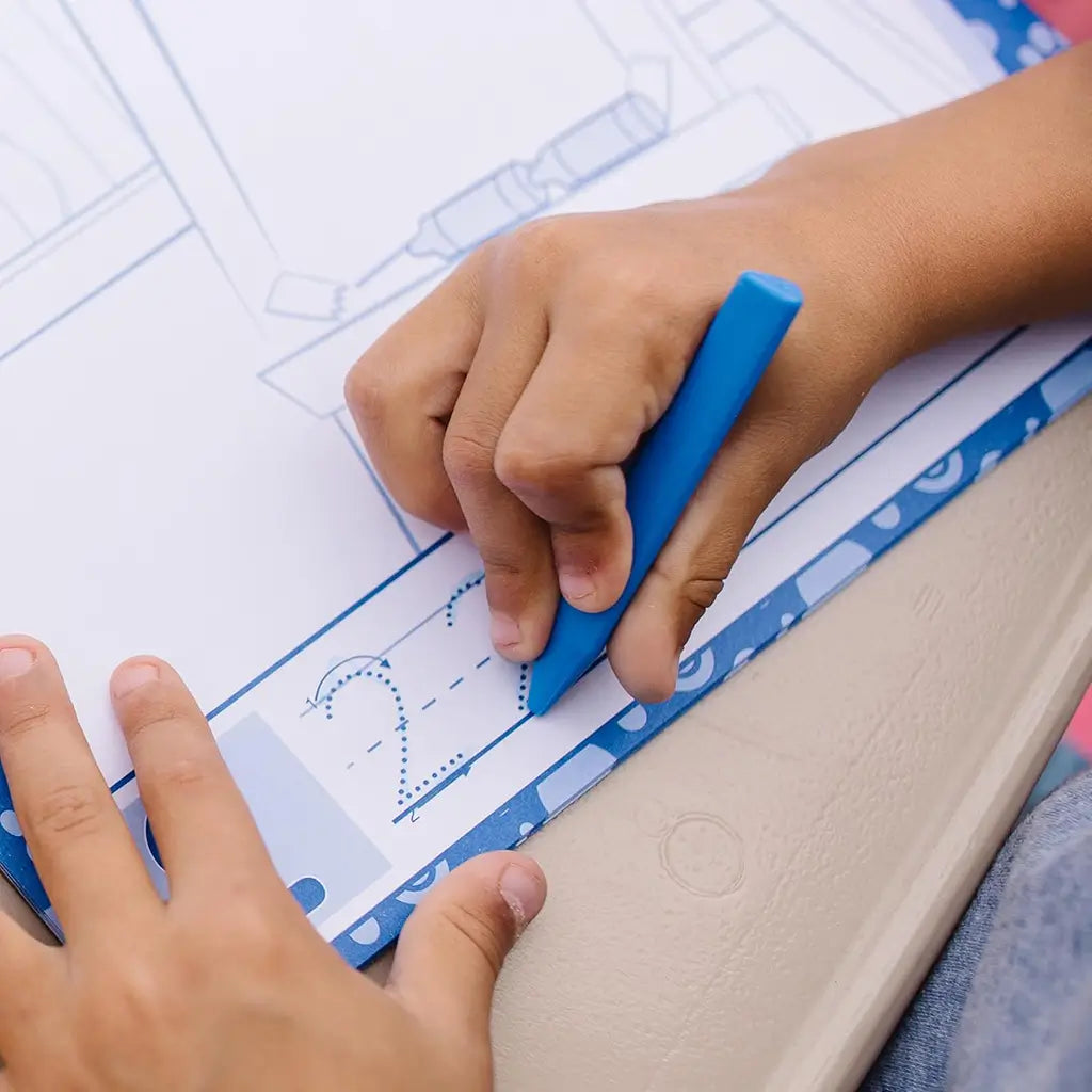 A child practices tracing numbers with a blue triangular crayon from the Melissa & Doug Blue’s Clues & You! stamp activity set, improving fine motor skills and early writing confidence.