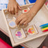 Close-up of Melissa & Doug Blue’s Clues & You! wooden stamps in a natural wood tray, showing colorful character tops like Blue, Magenta, and Mailbox, promoting easy cleanup and organized creative play.