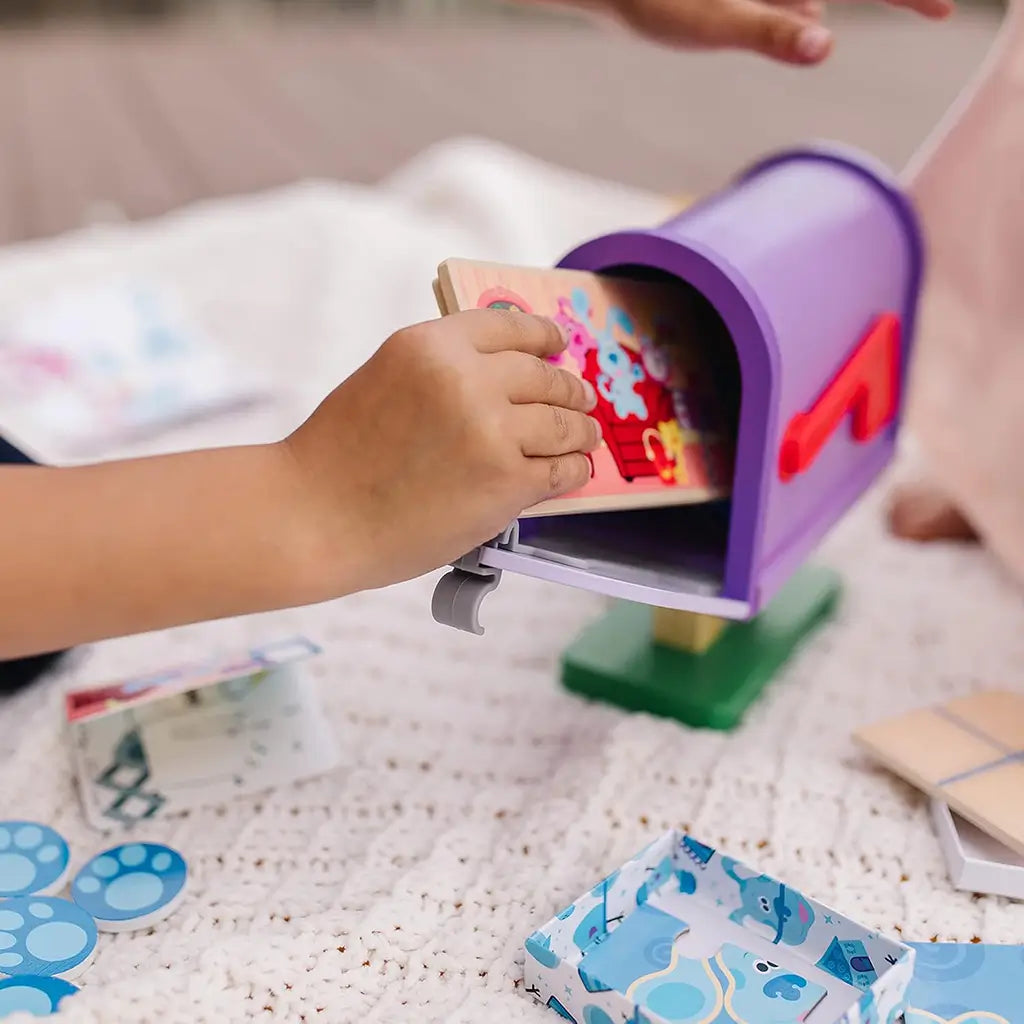 Children place a wooden postcard into the Melissa & Doug Blue’s Clues & You! mailbox, exploring pretend mail delivery, creativity, and teamwork in interactive, hands-on imaginative play.