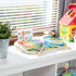 Melissa & Doug Blue’s Clues & You! music maker board displayed on a white shelf with natural light, showing colorful musical instruments and cards, blending playful design with early sound learning.