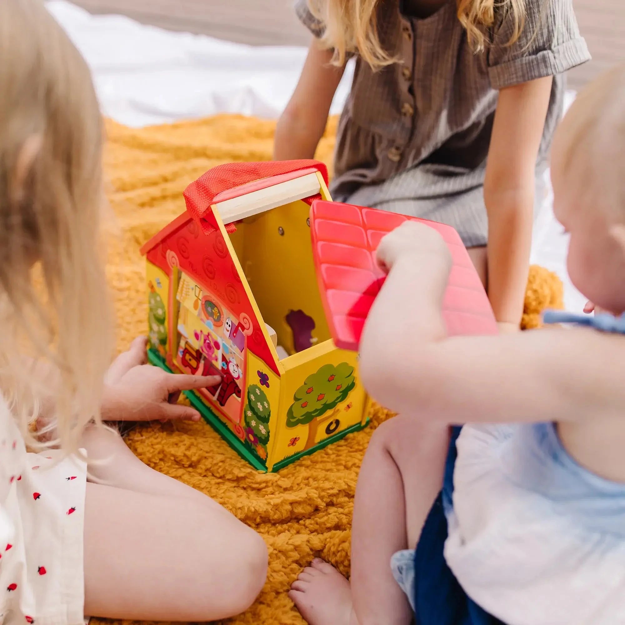 Toddlers playing with Blue’s Clues take-along house toy, lifting the roof and exploring puzzle blocks and shape sorter features during group play.