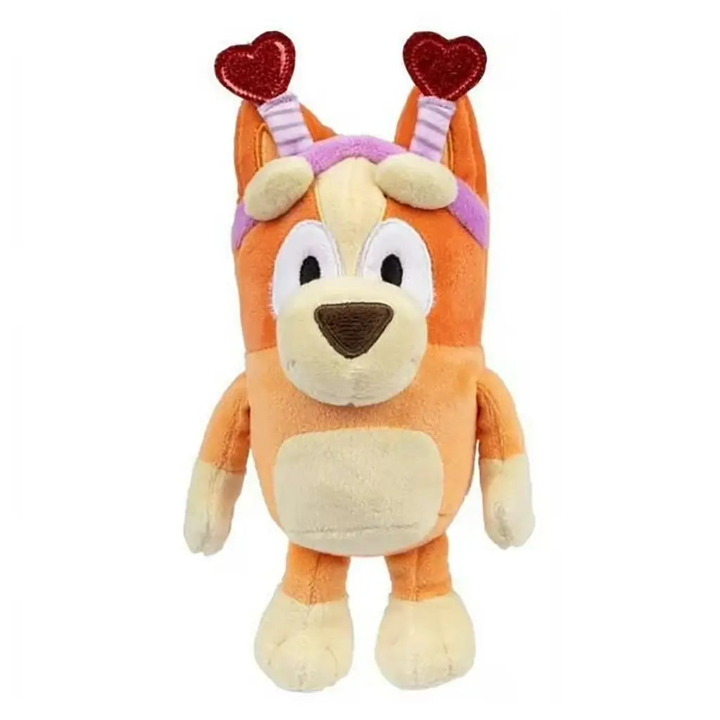 Smoochy Kiss Bingo plush toy in orange and cream fabric features a rounded dog shape with soft velvety texture and a pink headband topped with glittery red heart antennae, posed clearly on a white background.