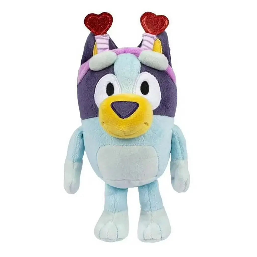 Smoochy Kiss Bluey plush toy in soft light-blue and navy fabric features a rounded dog shape with a yellow muzzle, embroidered eyes, and a pink headband topped with glittery red heart antennae against a white background.