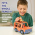 Child plays with Bluey Heeler 4WD vehicle, placing Chilli on the roof of the orange toy car that fits four figures, shown in a softly lit indoor room with subtle background shapes.