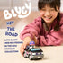 Bluey Muffin vehicle playset lifestyle image showing a smiling child pushing the black and gray convertible toy with Muffin figure seated inside, demonstrating hands-on play on a soft indoor floor.