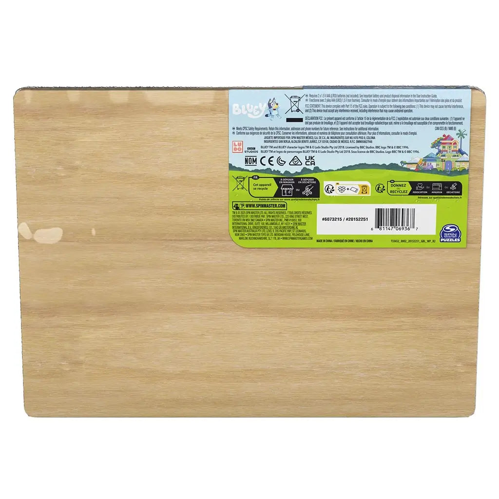 Bluey wooden sound puzzle back panel in light tan wood texture with rectangular form, featuring printed product label, safety icons, barcode, and Spin Master branding on a clean neutral background.