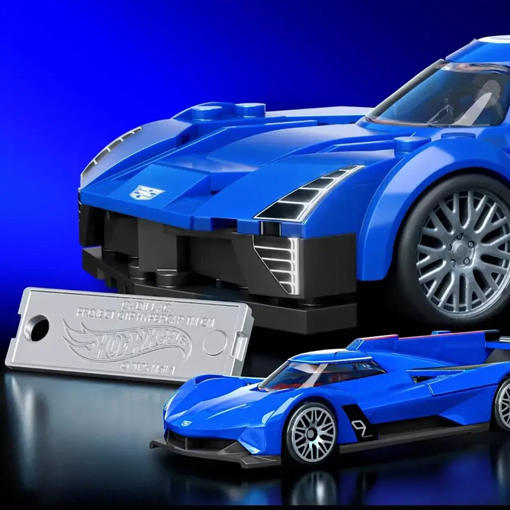 Hot Wheels Cadillac Project GTP Hypercar in blue brick form pairs with a smaller die-cast model and silver display plate, set against a vivid blue studio backdrop.