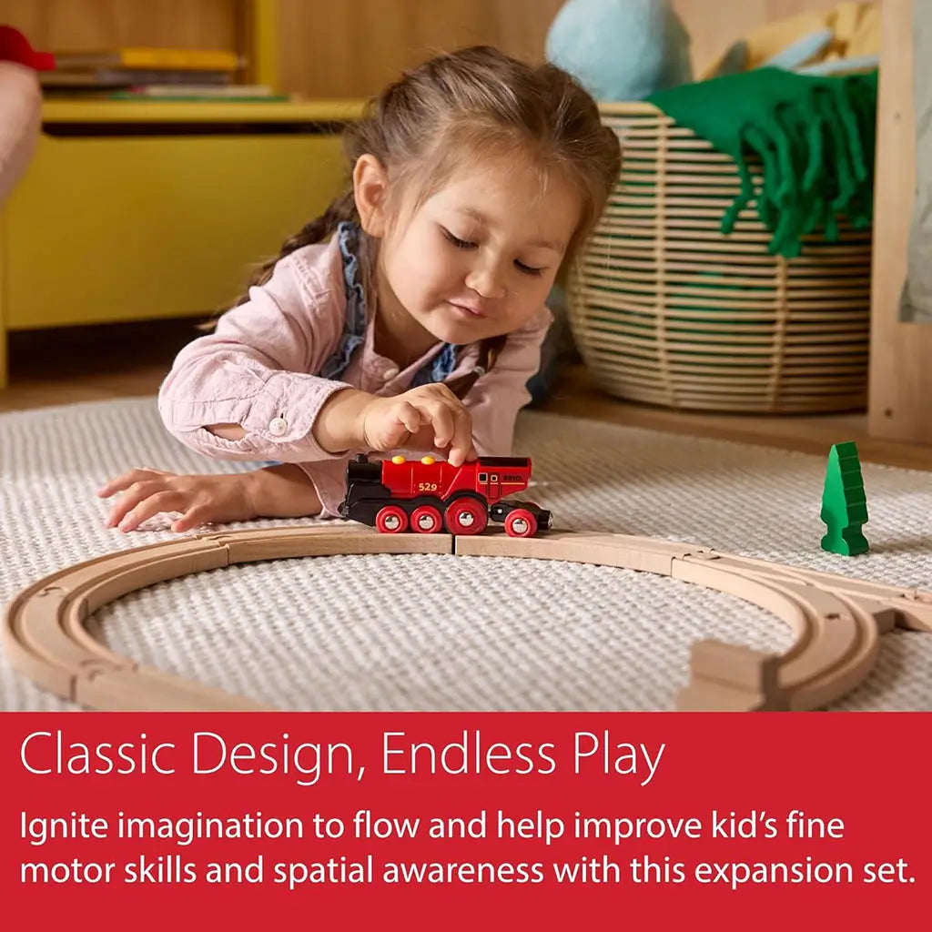 Young girl playing with a red BRIO wooden train on circular tracks, enhancing creativity, fine motor skills, and spatial awareness while engaging in imaginative play.
