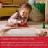 Young girl playing with a red BRIO wooden train on circular tracks, enhancing creativity, fine motor skills, and spatial awareness while engaging in imaginative play.