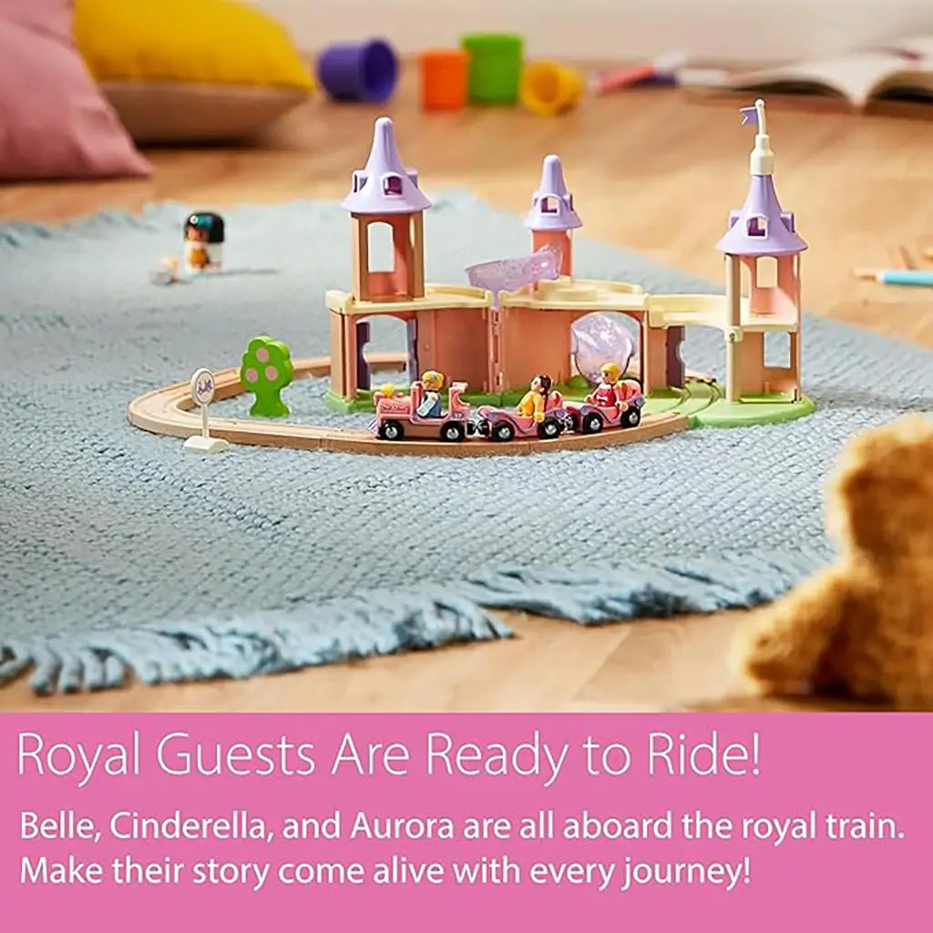 BRIO Disney Princess Castle set placed on a rug, showing pink train with princess figures riding through pastel castle towers, wooden track, and small tree accessory.
