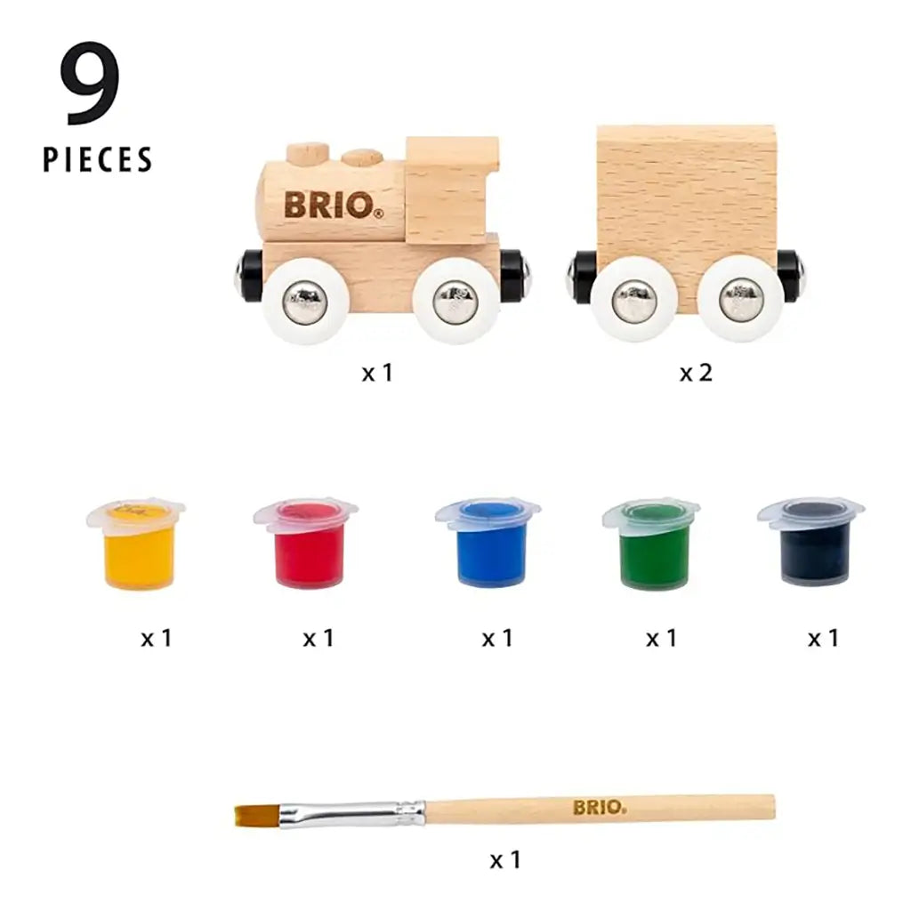 Unassembled BRIO paint train kit showing nine pieces, including a natural wood locomotive, two train cars, five colored paint pots, and a branded wooden brush.