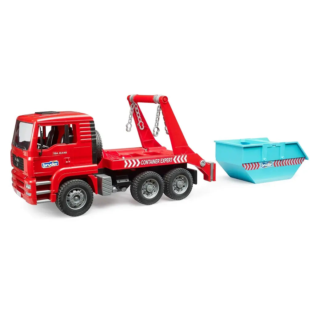 Bruder MAN TGA skip container truck toy in red plastic with turquoise, silver, and black details, shown beside a detached blue skip bin with hanging lift chains on a white background.