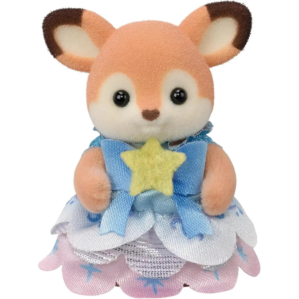 Calico Critters baby deer figure features soft tan flocked texture with cream face, large brown eyes, and blue satin dress with yellow star and layered pastel skirt on white background.