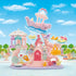 Calico Critters Baby Mermaid Castle playset features pastel pink and lavender plastic castle with blue wave slide, shell details, carousel ride, and small animal figures in underwater themed park setting.