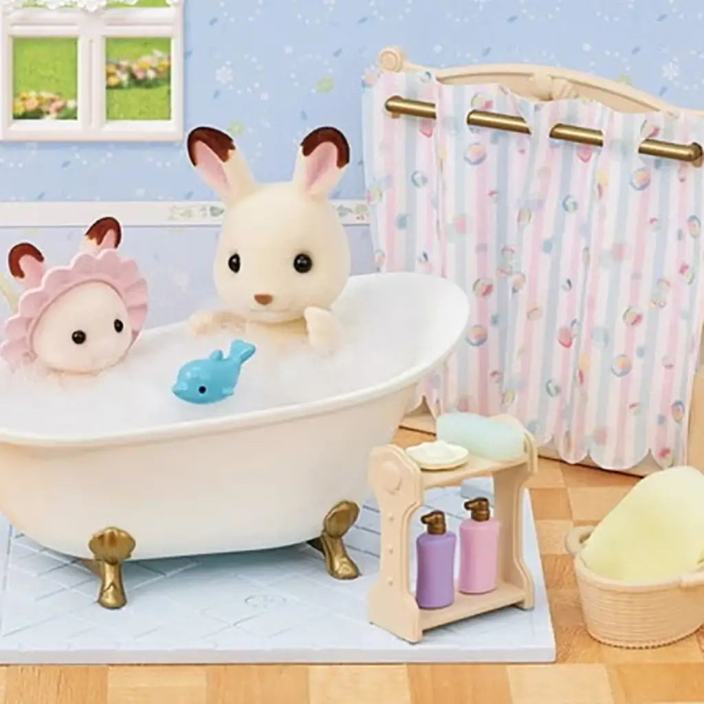 Calico Critters bath set display with white rabbit figurines in a white clawfoot tub, pastel shower curtain, soap bottles, towel basket, and toy fish in a dollhouse bathroom scene.