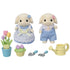 Calico Critters toy set includes two cream rabbit figures in blue gingham outfits, tulip flowers in pots, gardening tools, and a yellow watering can arranged neatly.