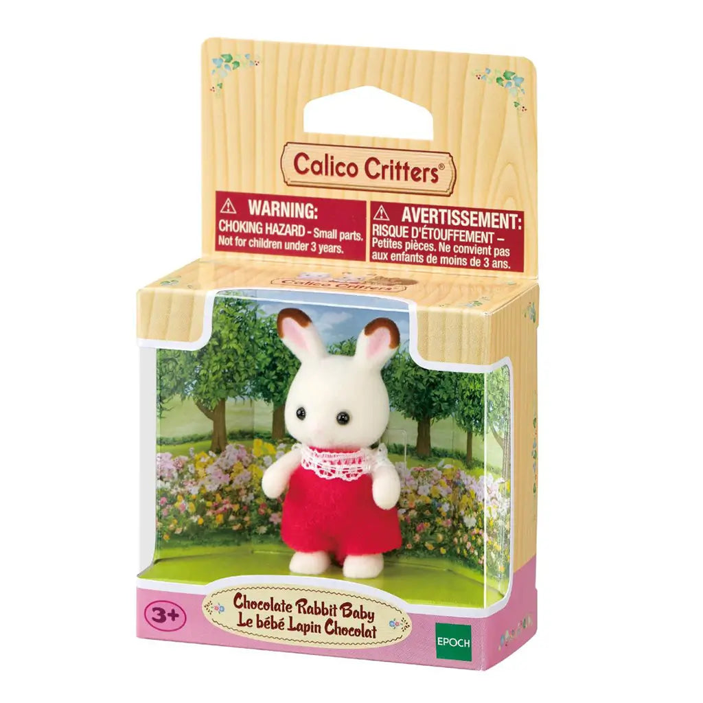 Calico Critters Chocolate Rabbit Baby package displays a cream flocked rabbit in red fabric overalls with white lace trim, presented in a garden-themed retail box.