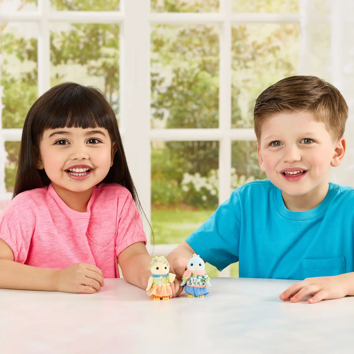 Calico Critters Citrus Bird Family figures feature soft pastel yellow and blue flocked bird dolls in fruit print outfits as smiling children play at table in bright window lit room setting.